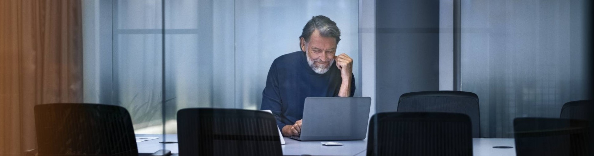 Äldre man med laptop i konferensrum.